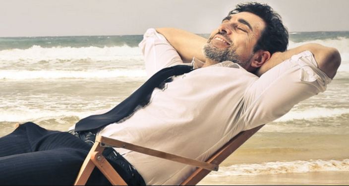 Homme assis sur un transat devant la plage